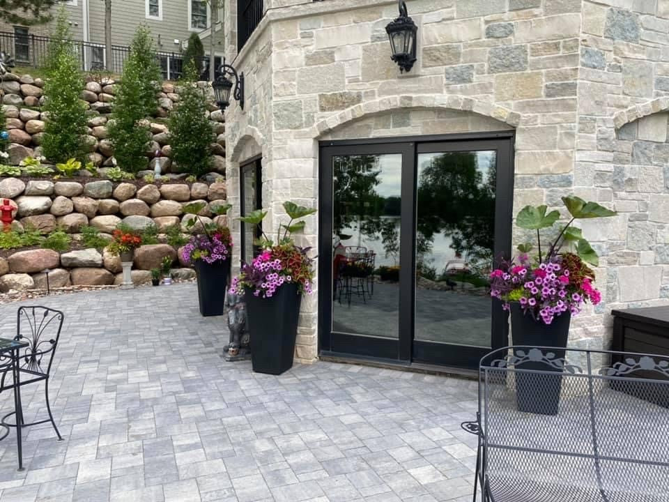 Outdoor patio area with stone walls, potted plants, and a glass door.