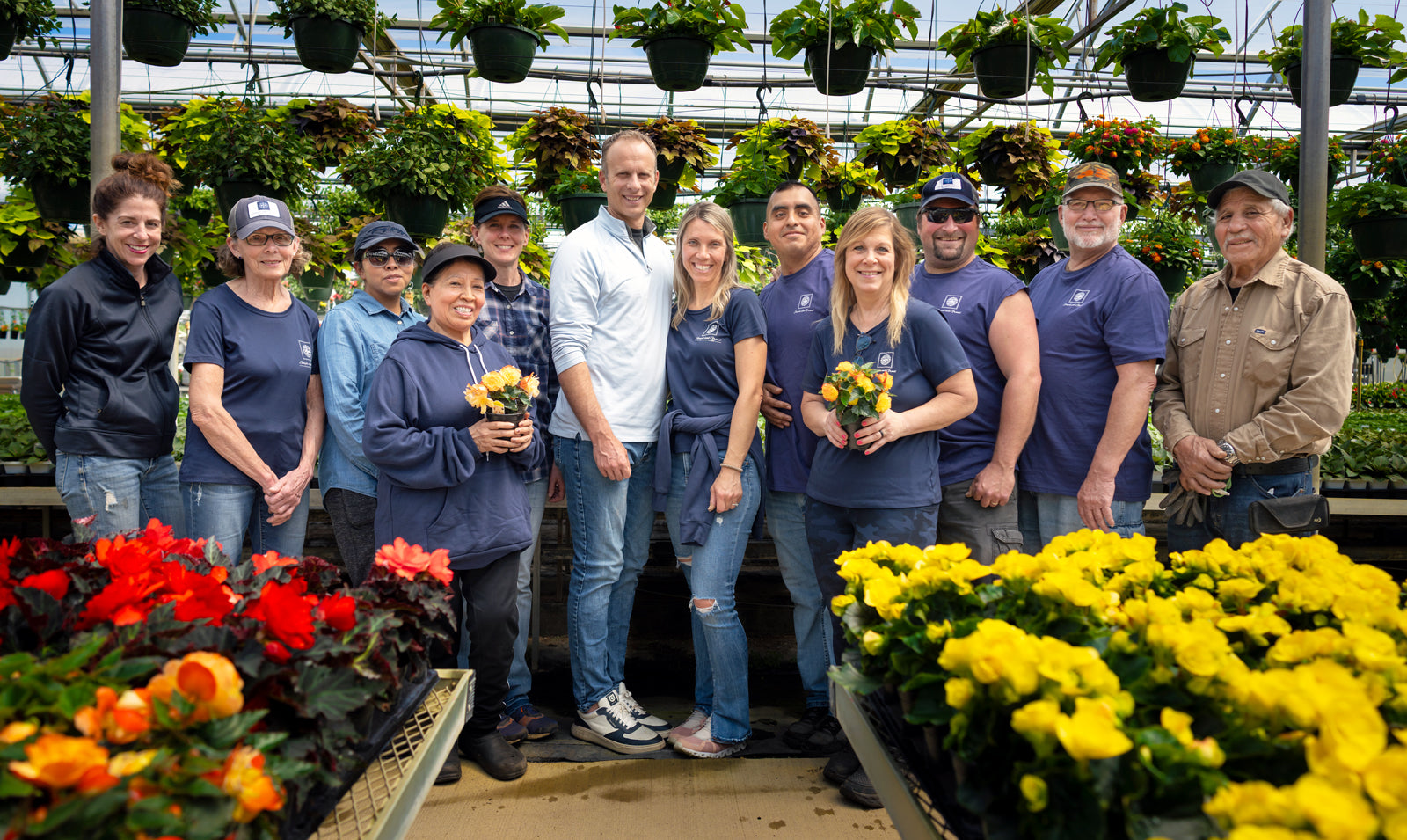 Group of people posing in a greenhouse with flowers